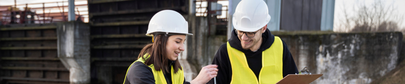 Two engineers talking on-site, wearing hi-vis vests and hard hats. Contact Aquasentry for information on liquid containment management.